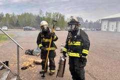 Two firefighters in full gear on paved surface — kitchen fire May 2024
